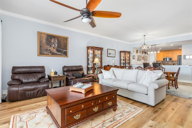 living room with crown molding, ceiling fan with notable chandelier, and light hardwood / wood-style flooring