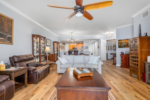 living room featuring crown molding, ceiling fan with notable chandelier, and light hardwood / wood-style floors