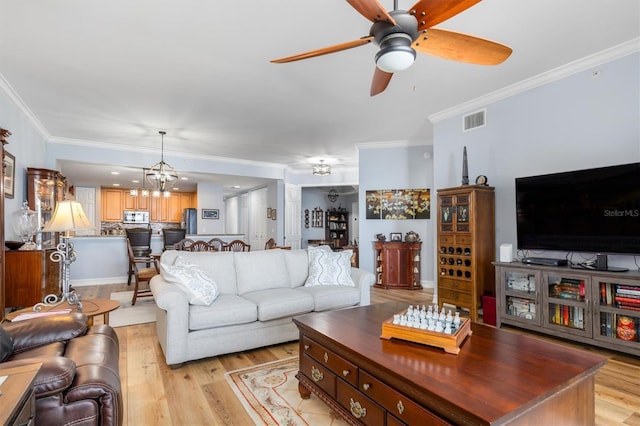 living room featuring crown molding, ceiling fan with notable chandelier, and light hardwood / wood-style flooring