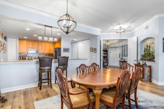 dining area with an inviting chandelier, crown molding, and light hardwood / wood-style floors