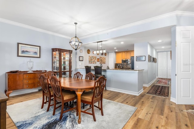 dining area with crown molding, a chandelier, and light hardwood / wood-style floors