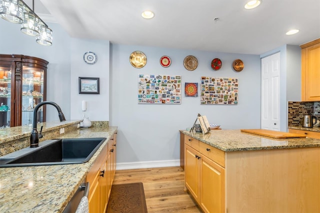 kitchen featuring sink, light stone counters, light brown cabinetry, and light hardwood / wood-style flooring