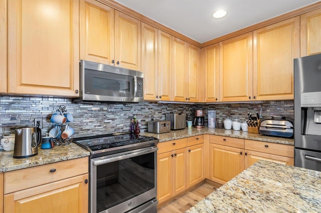 kitchen featuring stainless steel appliances, light stone countertops, and backsplash