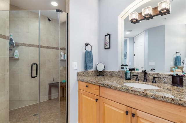 bathroom featuring a shower with door and vanity