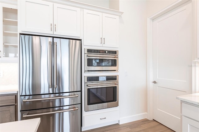 kitchen featuring white cabinetry, light hardwood / wood-style flooring, light stone countertops, and appliances with stainless steel finishes