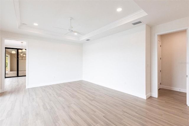 spare room with crown molding, ceiling fan with notable chandelier, a raised ceiling, and light wood-type flooring