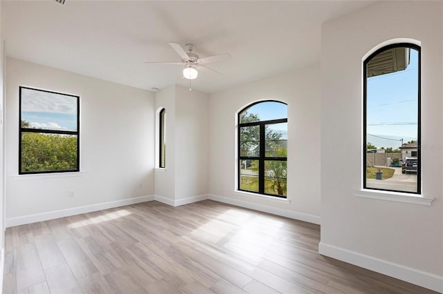 empty room with ceiling fan and light hardwood / wood-style flooring