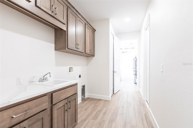 washroom with sink, cabinets, light hardwood / wood-style floors, hookup for a washing machine, and electric dryer hookup