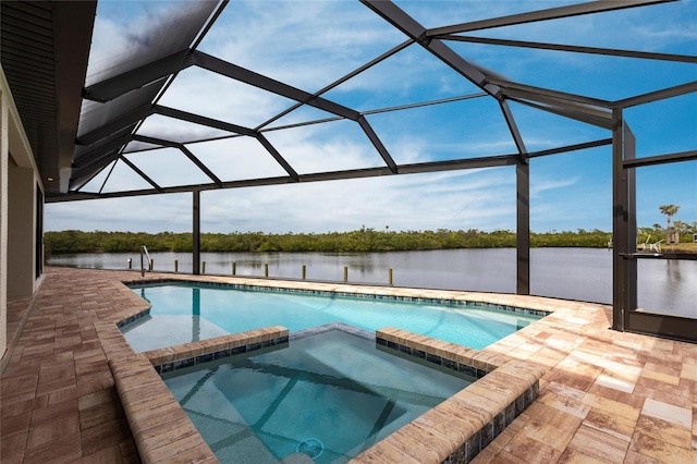 view of pool with an in ground hot tub, a water view, glass enclosure, and a patio area