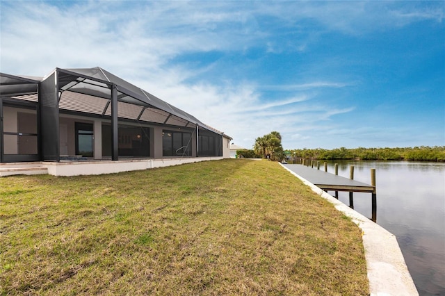 view of yard with a water view, a dock, and glass enclosure