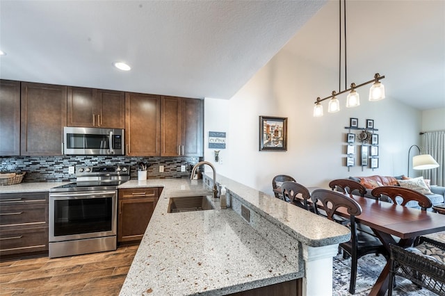 kitchen with appliances with stainless steel finishes, decorative light fixtures, sink, decorative backsplash, and dark wood-type flooring