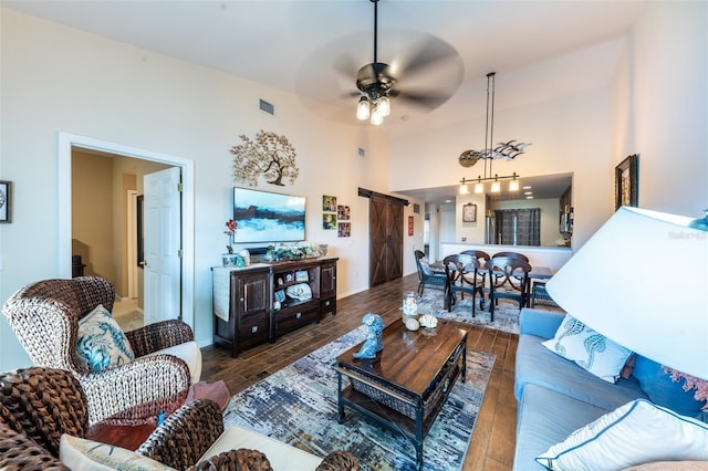 living room with dark hardwood / wood-style flooring, a towering ceiling, and ceiling fan