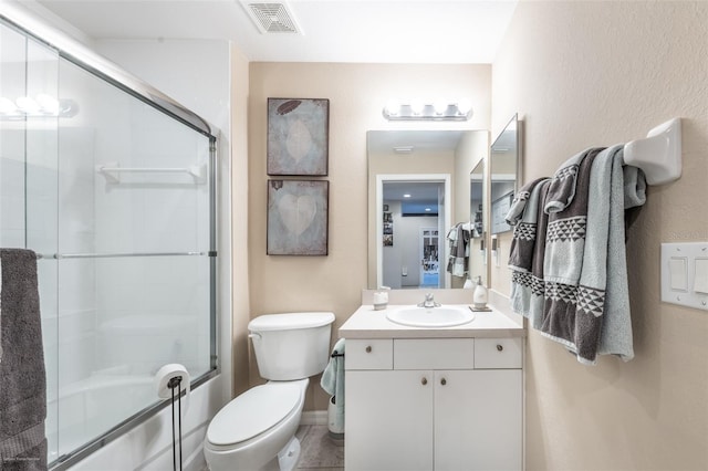 full bathroom featuring vanity, bath / shower combo with glass door, and toilet