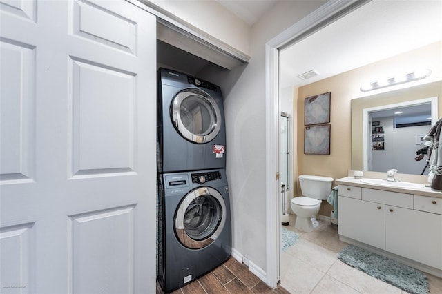 washroom with stacked washer / drying machine, sink, and light hardwood / wood-style floors