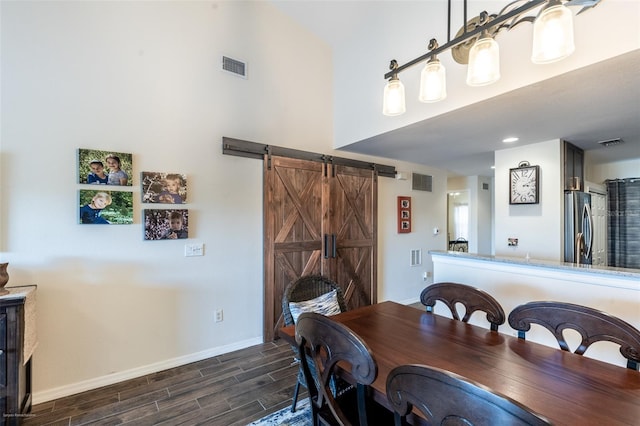 dining space featuring a barn door and a towering ceiling