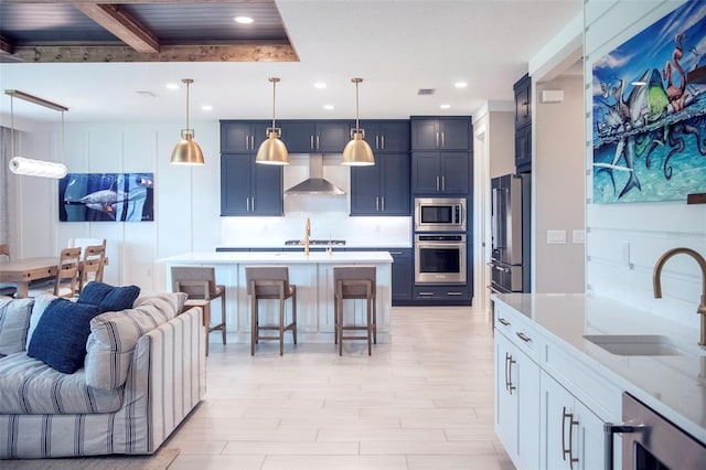 kitchen with sink, a breakfast bar area, hanging light fixtures, stainless steel appliances, and wall chimney range hood