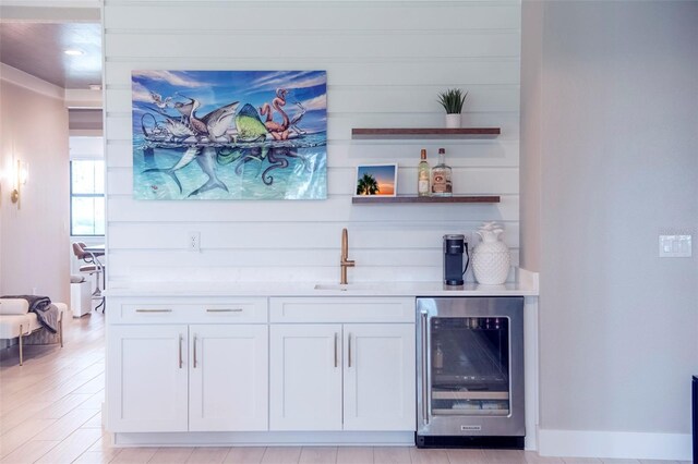 bar with sink, white cabinets, and beverage cooler