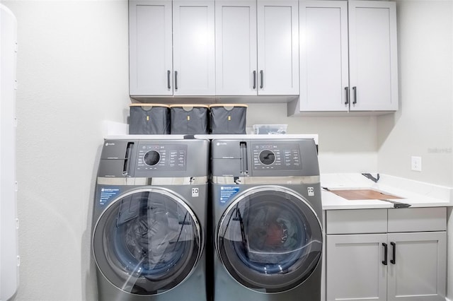 washroom featuring sink, cabinets, and washer and clothes dryer