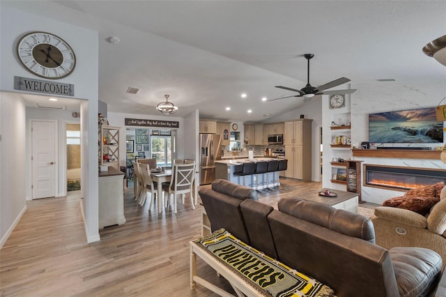 living room featuring ceiling fan, vaulted ceiling, and light hardwood / wood-style flooring