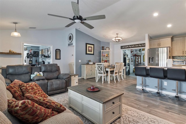 living room featuring ceiling fan, lofted ceiling, and light hardwood / wood-style floors