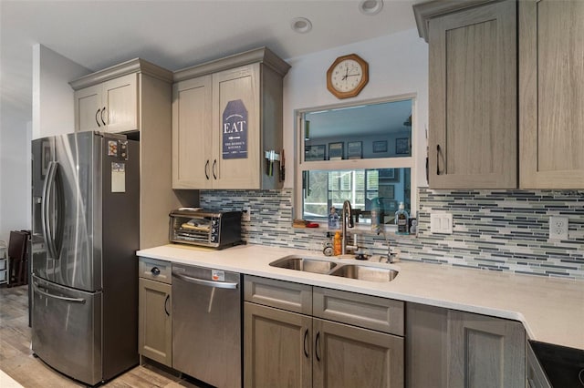 kitchen with appliances with stainless steel finishes, light hardwood / wood-style floors, sink, and decorative backsplash