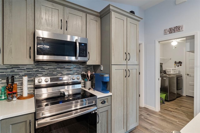 kitchen with gray cabinets, appliances with stainless steel finishes, backsplash, light hardwood / wood-style floors, and washer and dryer