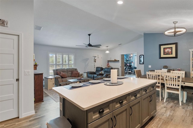 kitchen featuring lofted ceiling, a center island, dark brown cabinetry, ceiling fan, and light wood-type flooring