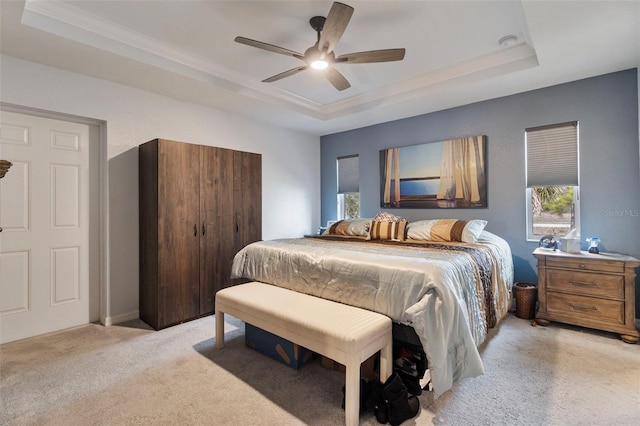 carpeted bedroom featuring a raised ceiling and ceiling fan