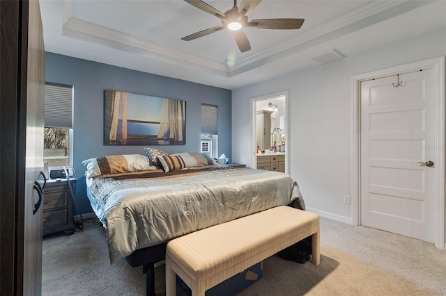 bedroom with ensuite bath, light carpet, ornamental molding, a tray ceiling, and ceiling fan