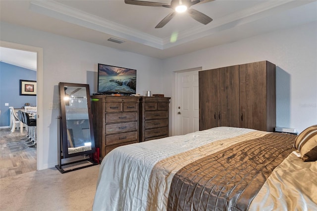 bedroom with crown molding, light carpet, ceiling fan, and a tray ceiling