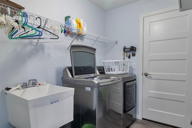 laundry area featuring wood-type flooring, sink, and washer and clothes dryer