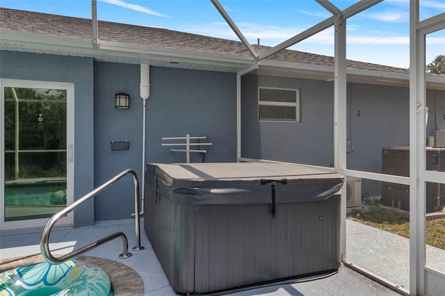 exterior space featuring a hot tub, cooling unit, and glass enclosure