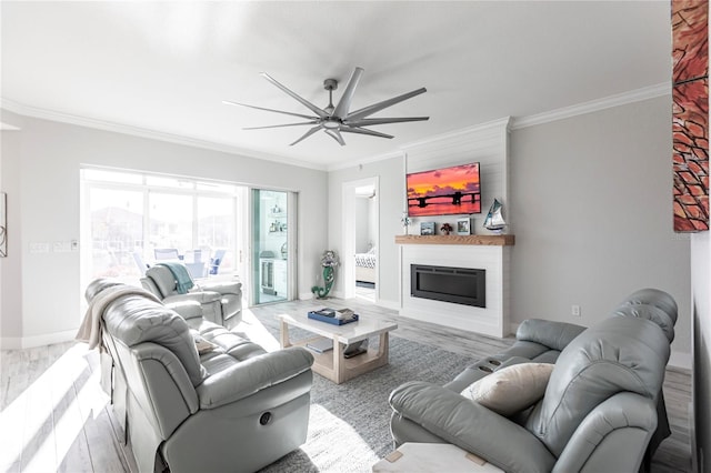 living room featuring crown molding, light hardwood / wood-style floors, a large fireplace, and ceiling fan