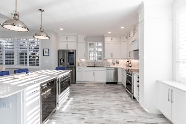 kitchen featuring pendant lighting, sink, white cabinetry, stainless steel appliances, and wine cooler