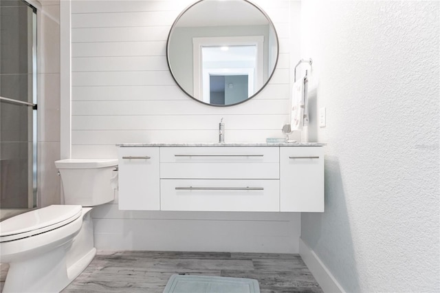 bathroom with an enclosed shower, wood-type flooring, vanity, and toilet