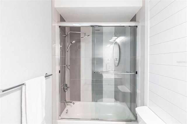 bathroom featuring bath / shower combo with glass door and toilet