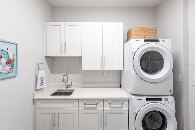 clothes washing area with cabinets, stacked washing maching and dryer, and sink