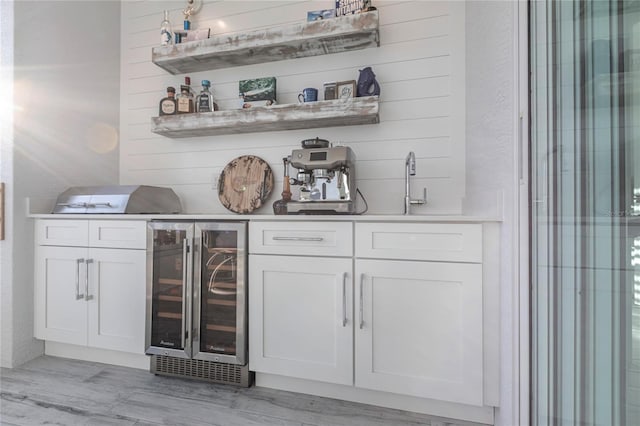 bar with white cabinets, wine cooler, and light hardwood / wood-style floors