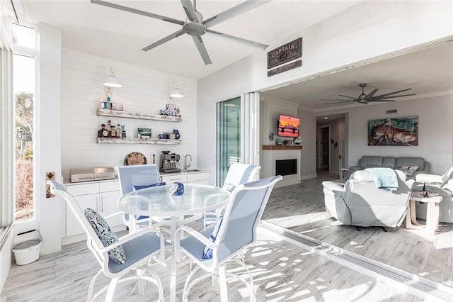 dining area featuring light hardwood / wood-style flooring, ornamental molding, and ceiling fan