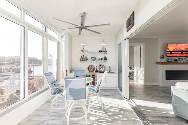 sunroom with a fireplace, a wealth of natural light, and ceiling fan