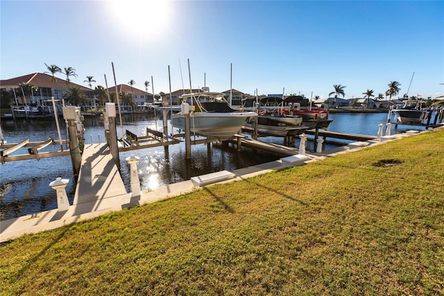 view of dock with a water view and a yard