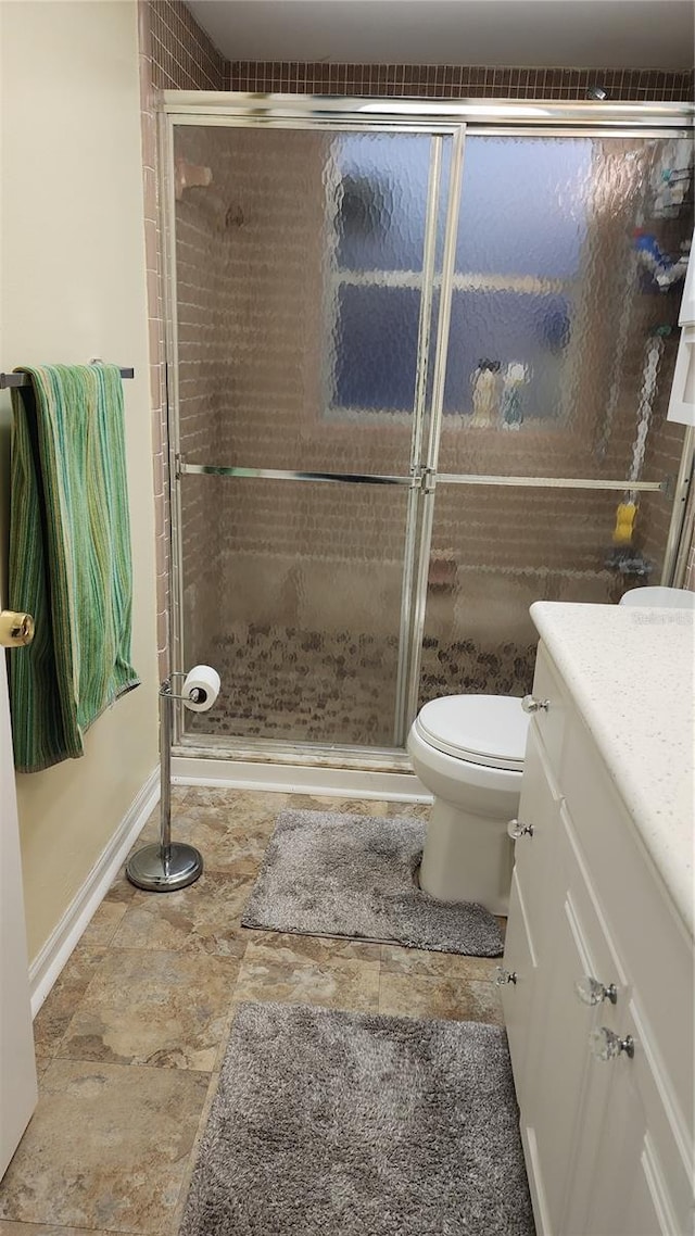 bathroom with vanity, toilet, and a shower with shower door