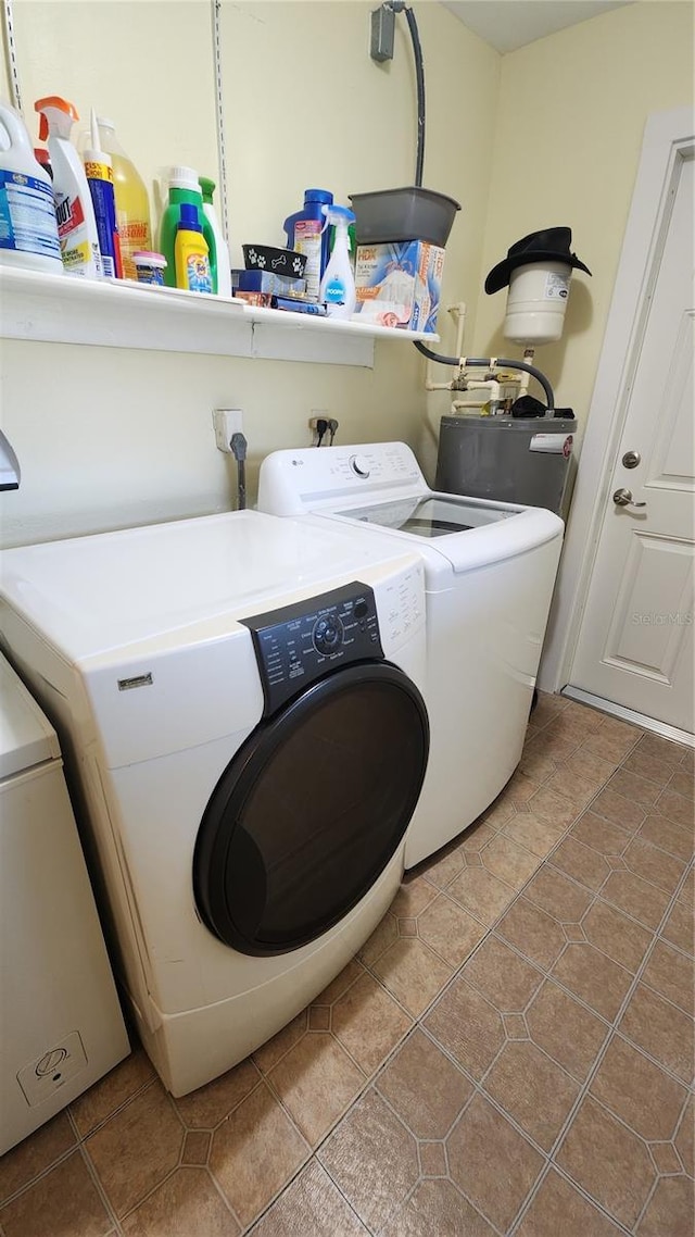 clothes washing area with independent washer and dryer, tile patterned floors, and water heater