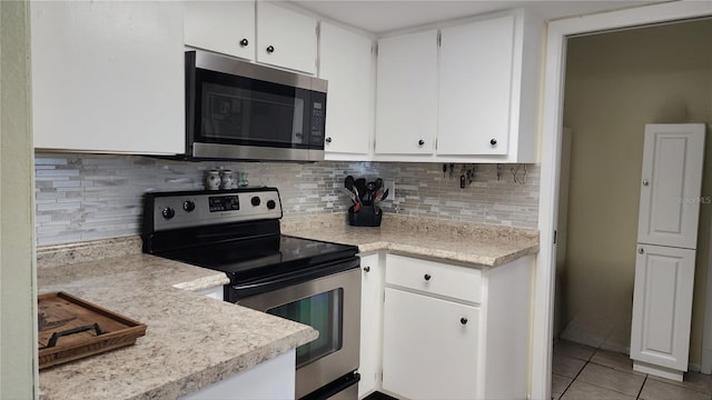 kitchen with white cabinetry, appliances with stainless steel finishes, light tile patterned flooring, and backsplash