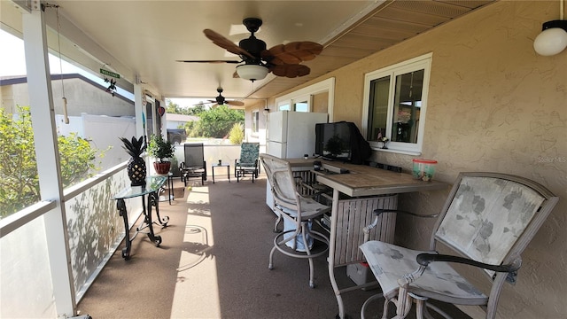 view of patio / terrace featuring a bar, radiator, and ceiling fan