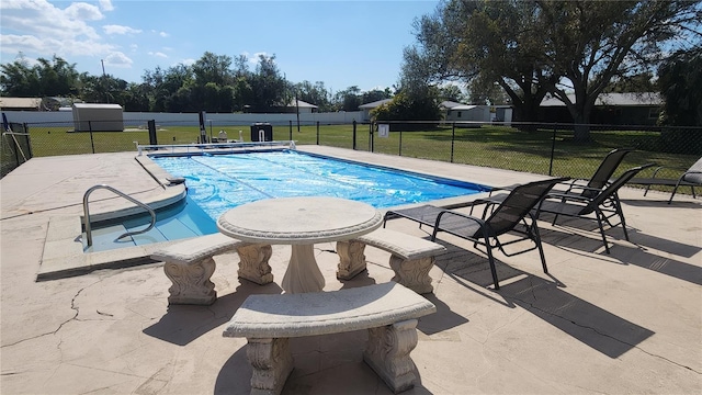 view of pool with a patio area and a lawn