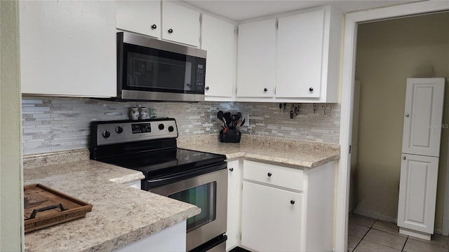 181 Coconut St, Punta Gorda, FL 33980 - kitchen with appliances with stainless steel finishes, light countertops, light tile patterned flooring, white cabinets, and tasteful backsplash
