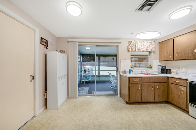 kitchen featuring light carpet, sink, and range