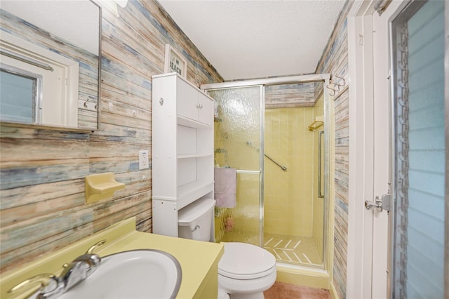 bathroom with a shower with door, vanity, a textured ceiling, and toilet