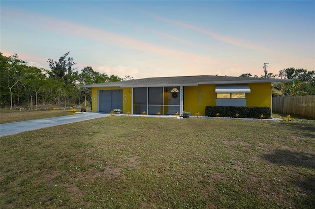 ranch-style home featuring a garage and a lawn